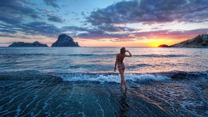 Девушка заходит в море на закате